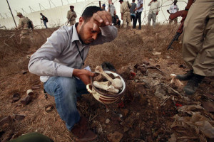 Man collects human remains at the site of a mass grave in Tripoli
