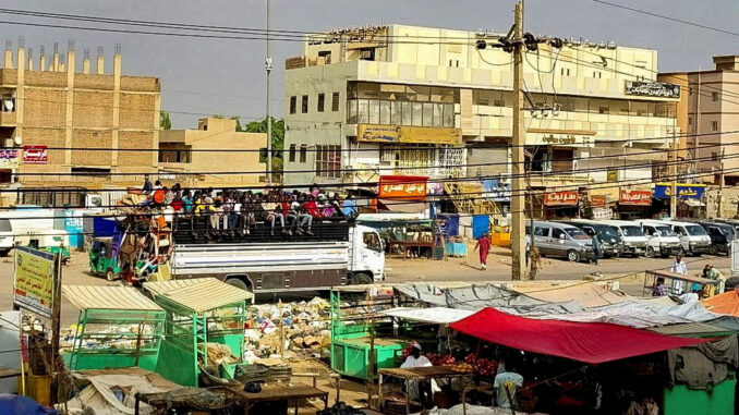 FILE PHOTO: People gather to ride trucks to flee outside Khartoum, in South Khartoum locality